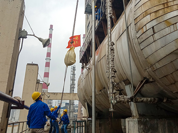 5月10日中午，在動(dòng)力車間三期工藝除氧器地面，黨員突擊隊(duì)隊(duì)員用滑輪往工藝除氧器平臺(tái)運(yùn)送鋼絲網(wǎng)，用以纏繞新填料.jpg